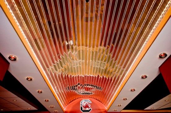 Barrel vault ceiling connecting the Players Lounge concourse and locker room, created using Chicago Metallic's Planar? Linear Metal Panels with a Reflective Chrome Finish and Open Plenum CubeGrid? in a garnet color to match the USC team colors