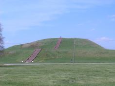 Monk's Mound, created by the Mississippian culture, is located at Cahokia. The staircase you see is new, but built to follow the course of the original wooden stairs. Also visible is a road and power lines cutting through the site.