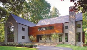 The home's stripped-down gables, muntined windows, and stone landscape walls and chimney establish firm roots in its traditional neighborhood.