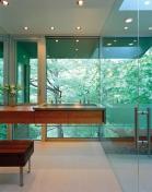 A mirrored wall opposite the shower doubles the appearance of the room's size while also concealing pipes and wires. A large skylight over the shower balances the quality of light spilling through the diaphanous wall.
