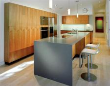 Engineered stone countertops in sedate gray provide a calm counterpoint to lively wood grains on cabinets and floors.