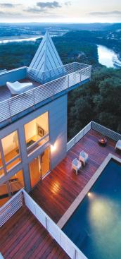The multi-level house opens up toward the pool deck, with windows and balconies that overlook the space from several angles.