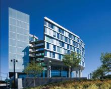 Glass walls overhang a central courtyard, simultaneously creating openness and a sense of boundary. The studio tower (left side of image) overlooks a highway.