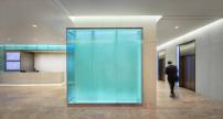 A backlit, glass-walled corner guides building patrons to the elevator bank.