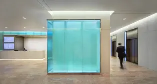 A backlit, glass-walled corner guides building patrons to the elevator bank.