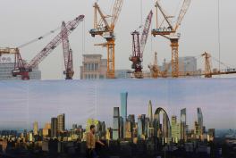 A man walks past a billboard display showing the scenic of Central Business District near a construction site in Beijing. China's growth could decline to close to 7 percent next year but Beijing should focus on overhauling its economy instead of trying to stick to official growth targets, the World Bank said Wednesday.