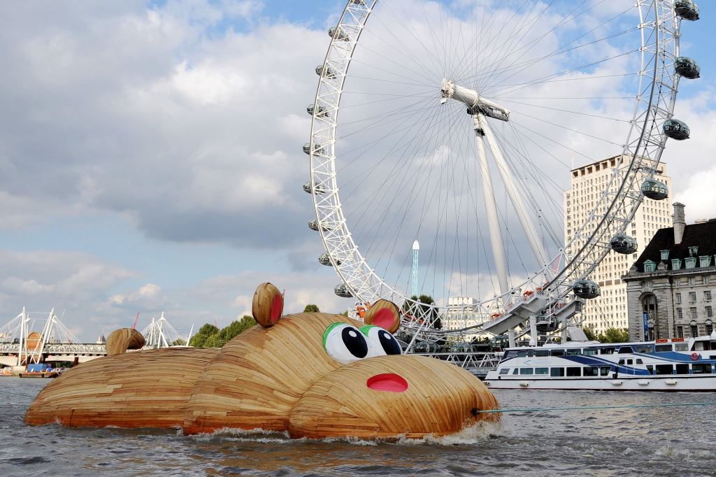 The 'HippopoThames' sculpture is towed past the London Eye. Florentijn Hofman, a Dutch artist known for his giant Rubber Duck project, designed the 69-foot-long hippo for the River Thames. The artwork was inspired by research from the National History Museum that found hippos once occupied the river.