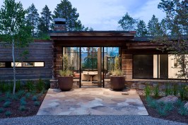 Exterior, horizontal, front entry at twilight looking into living room and view out windows to mountains and forest, Rosenthal residence, Wilson, Wyoming; Ward + Blake Architects