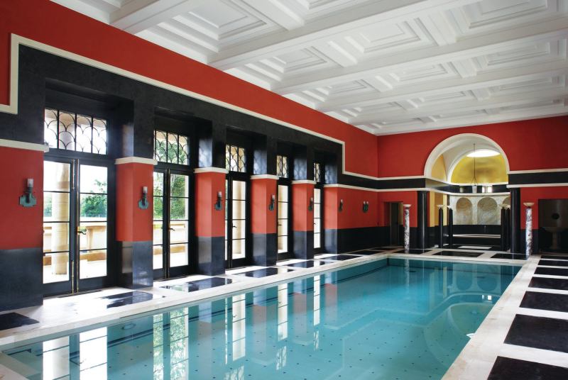 The marble floors continue into the pool hall, which is lined with Pompeian red walls. The hot tub in the apse is flanked by a sauna and a steam room.