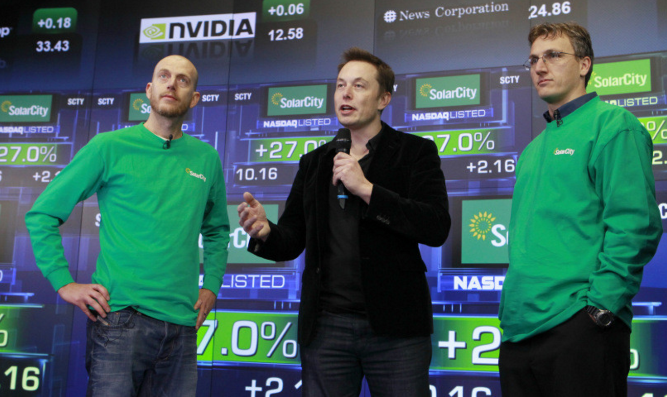 Founder & COO Peter Rive, Chairman Elon Musk , SolarCity Founder & CEO Lyndon Rive speak at the company’s IPO at the NASDAQ stock exchange on December 13, 2012 in Manhattan, New York. SolarCity is a leader of distributed clean energy and will trade under SCTY. (Mark Von Holden/AP Images for SolarCity)