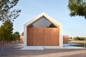 From the front, the Cottage in the Vineyard looks like a simple gabled structure, with a concrete frame that is as tall as it is wide.