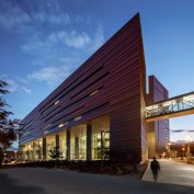 Exterior view at night, showing bridge to existing campus building