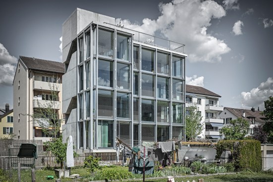 The four-story building, shown from the southwest, is enveloped by a mostly glass façade.
