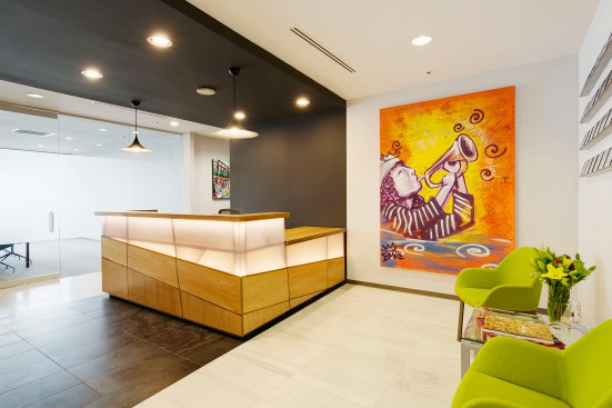 The "reception threshold" featuring the custom reception desk designed and built by NANO LLC from 3form Chroma and cypress plywood and selected artwork on loan from the Ogden Museum of Southern Art.