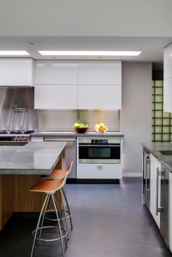 The concrete floor blends seamlessly with the modern aesthetic of the kitchen and all of its cabinetry. This photo captures one of the kitchen alleys, between the island and the coffee station.