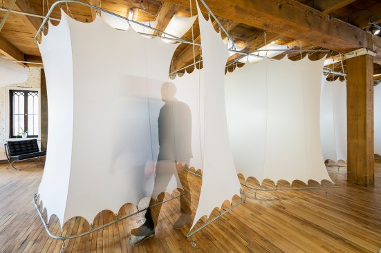 Stretched white spandex pods on metal frames create a flexible work space in a chiropractor's office - man walking out of pod
