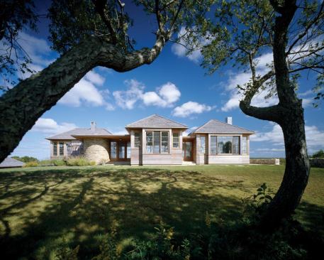 The house's volumes, topped with yellow cedar hipped roofs, separate the private, semi-private, and public functions and enhance the sense of light and scale. Top-hinged awning and sliding teak windows control air flow.