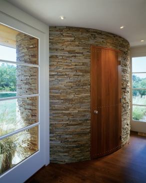 Interrupting the house's transparent corner, an abstracted stone "sugar mill" is continuous from outside to inside, where it holds a powder room.