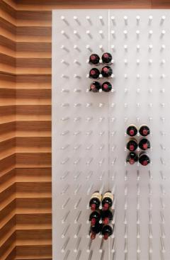The wine room, in an alcove behind the kitchen, is fitted with a translucent panel lit from above and behind. The bottles rest on aluminum rods.