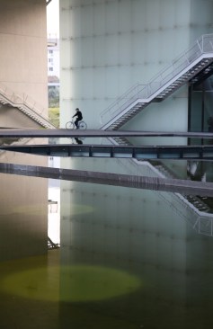 A cyclist pedals beneath the building.