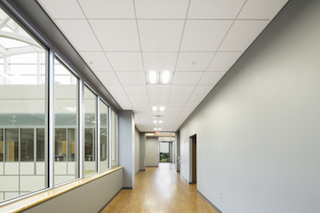 ROCKFON’s ceilings systems create quiet, comfortable learning spaces throughout ASU’s new HSS facility and meet seismic requirements. Arkansas State University’s Humanities and Social Sciences building will greet its first students in the upcoming 2015-16 academic year. AMR Architects designed the building’s exterior to complement the campus’ historic architecture and its modern interior to offer quiet, comfortable learning spaces. Helping accomplish these goals, the new building features ROCKFON’s ceilings systems throughout its 120,000-square-foot, four-story facility. Campus Centerpiece “The new building will be at the heart of every ASU student’s experience on this campus,” said Dr. Lauri Umansky, former dean of the Humanities and Social Sciences (HSS). “Our courses engage students deeply in the world around them. And we have a first-rate faculty. That we will soon be able to offer this kind of high-quality education from a spectacular, state-of-the-art facility is truly exciting.” The HSS building serves as a centerpiece linking Historic Mall to the west, the Caraway Mall to the south, and the new Campus Commons to the north. The structure dramatically defines the edges of multiple plazas and vistas. Inside, it encompasses more than 40 classrooms, laboratories, seminar rooms and approximately 140 faculty offices plus a large atrium for groups to gather. HSS will have 24 percent more space than offered by the building it replaces, Wilson Hall. Arkansas State University’s oldest building opening in 1932, Wilson Hall eventually will be adapted and renovated for other uses. Considered one of the largest instructional buildings on a university campus in the state of Arkansas, HSS has been constructed in four phases with an estimated budget of $36 million. The final phase was substantially completed in June 2015. This phase focused on the interior and site exterior and was completed in 16 months with Tate General Contractors. Tate worked with AMR on all four phases of the project. AMR also received architectural support from CahoonSteiling | Studio of Jonesboro, Arkansas. In total, AMR Architects was involved for more than 10 years on the project. The initial design was bid in 2003 and shelved due to budget constraints. With financial support from the governor and state legislature, the project first broke ground in Sept. 2008. Cost-Effective Performance + Aesthetics During the continued phased construction, the university incorporated some modifications as classroom count and size changed dramatically. Budgets remained top-of-mind in continuing from one phase to the next. AMR Architects employed value engineering methodologies to ensure the construction and materials maintained the project’s performance and aesthetic requirements, as well as provided the most cost-effective selections. In early 2014, as the fourth phase began, AMR Architects’ Jamie Borg, associate AIA, reviewed value-engineered options for the ceiling systems selections. The existing specifications called for an acoustic ceiling tile with a white finish that met the requirements for Seismic Design Categories D, E and F and the high Noise Reduction Coefficient (NRC) of 0.70. ROCKFON meets ASU’s goals for aesthetics, performance, schedule and budget.
