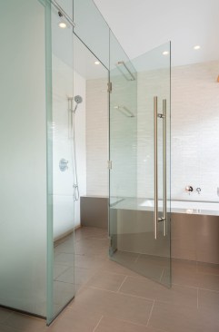 Shower is separated from tub area by tempered glass surround