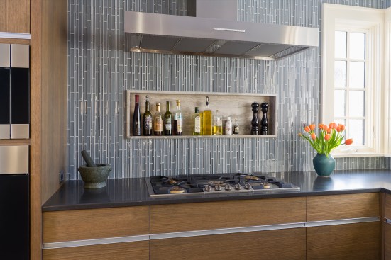 Corner of modern kitchen showing cooktop, window and unique backsplash tile