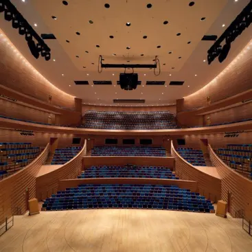 A view from the stage of Helzberg Hall looking out at the seating area. The hall is outfitted with both architectural lighting and theatrical lighting systems. The perimeter of the space is accented by PAR38 IR wallwashers that line the ceiling cove.