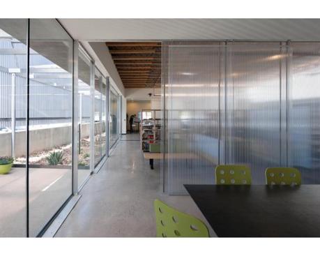 Floor to ceiling glass offers views of the courtyard, while sliding polycarbonate panels create private spaces inside.