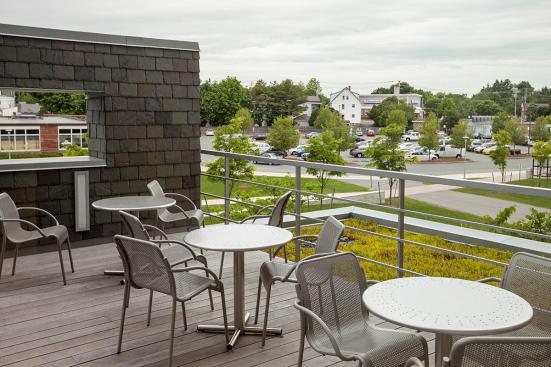 Cross tables with 30" round table tops with round perforations and 24" bases shown in Stainless Steel with Sandstone finish; Vista chairs shown with Aluminum Texture powdercoat at Salem State University, Salem, Massachusetts