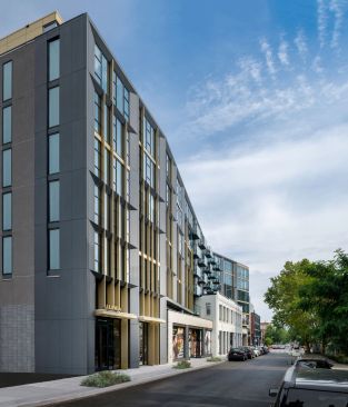 The north side view showcases the angular impact of the facade along the narrow side street.