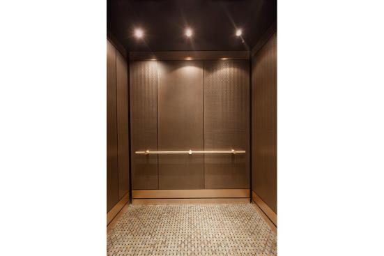LEVELe-105 Elevator Interior with main panels in Bonded Bronze with Dark Patina and Mazatl?n pattern; accent panels in Bonded Bronze with Dark Patina and custom pattern; Compass handrail in Satin Bronze at Residences at the InterContinental, Boston, Massachusetts