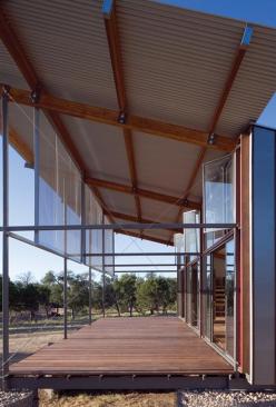 Oversized sunscreens hang down along the edge of the porch. The perforated-metal panels are left loose on one end to sway in the wind.