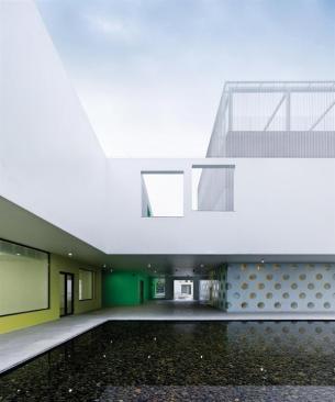 A+courtyard+with+a+large+reflecting+pool+serves+as+a+hub+for+several+of+the+building+volumes%2c+such+as+a+theater+and+dance+studios.