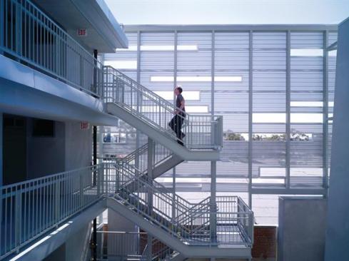 A perforated metal screen along the side of the building creates a dappled effect in the courtyards. The screen affords a degree of privacy while providing sightlines to the larger community.