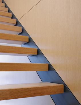 The steel stringers are set flush with the white oak paneling on one side and the plaster surface on the other.