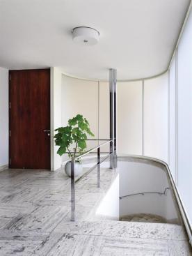The+street-level+entrance+leads+into+a+marble-lined+foyer+with+a+curving+stair+that+leads+down+to+the+main+level+of+the+house.