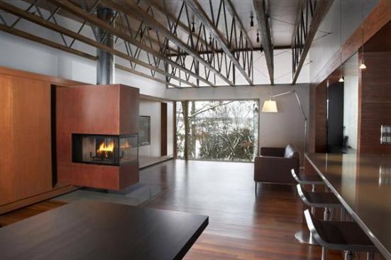 The living rooms Cor-Ten steel fireplace hovers above a flush hearth of clear-coated steel.
