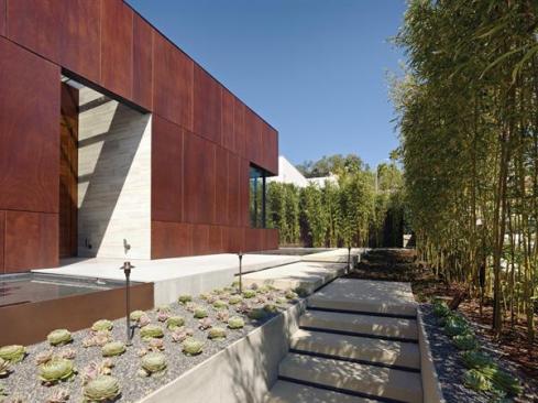 The Parlex rain screen provides a tonal counterpoint to the glass and stone. The interiors silver travertine wall meets a mitered wood corner outside the entryway.