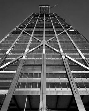 John Hancock Center Construction, Chicago, by Skidmore, Owings & Merrill. Designer Bruce Graham designed this towering skyscraper with structural engineer Fazlur Khan. It became public in 1965 and is used for commercial space, office space, apartments, parking, an observatory and more. It stands 1449 feet in the air and is recognized by its tapered silhouette and X bracing.