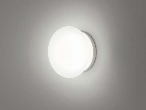 The Boccia lamp’s opal glass bowl is formed in the shape of a slightly flattened sphere. It can be fixed to a mirror or wall mounted. The lamp’s stainless steel mount comes in a black-anodized aluminum or white matte finish.