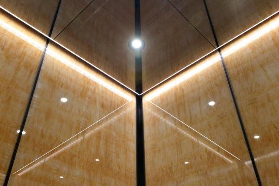 Elevator Ceiling in Fused Nickel Silver with Mirror finish; LED downlights and LED perimeter accent lighting; LEVELe-105 Elevator Interior with upper panels in ViviStone Honey Onyx, Standard finish at 176 Broadway, New York, New York