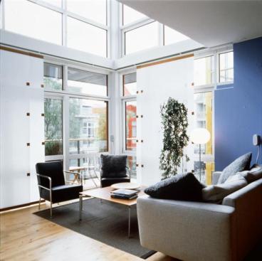 Glassy bays in the living room project into the garden and carry light into the kitchen; rolling screens allow for privacy.