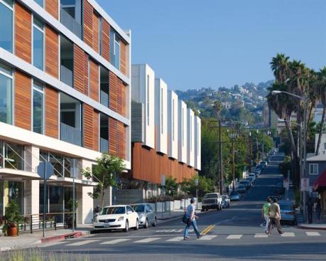 Vertical swaths of white corrugated metal help distinguish the townhouses from the flats, which feature horizontal wood screens that slide for privacy and sun control. 