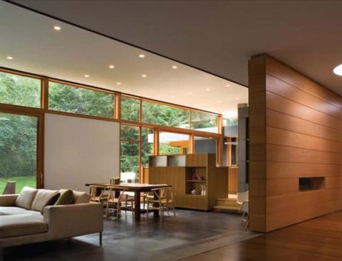Glass walls, blackened steel, and teak plywood cabinets let this mid 20th century home in a Seattle suburb blend with its leafy surroundings.