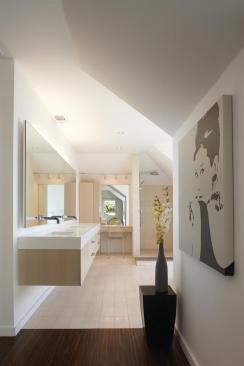 The master bathroom features a solid surface vanity atop a rift-cut white oak base. Limestone tiles line the floor and shower, while an ipe "rug" is set into the floor. 