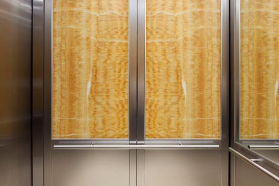 CabForms Series 2000-N Elevator Interior with upper inset panels in ViviStone Honey Onyx, Pearlex finish; lower inset panels in Stainless Steel, Linen finish; stiles and rails in Stainless Steel, Seastone finish; Sextant Handrail in Stippled Stainless Steel at the Woolworth Building, Eugene, Oregon