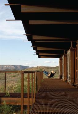 Practical, impervious, and low-tech, the cargo-container guest cabins are at home on the harsh Texas range. The five containers three bedrooms, a kitchen, and storage space are linked by a deck of steel bar grating with built-in bench and barbecue.