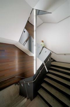 Interior Stairwell The egress stair serves double duty as the main public stair. Shaping the stairwell is a segmented, planar surface that seems to unfurl like a roll of curling ribbon. The painted steel plates function as a guardrail and are also bent to produce rigidity for the stair stringer and handrail supports. Risers are painted steel pans containing pouredin- place concrete treads with a matte sealer.
