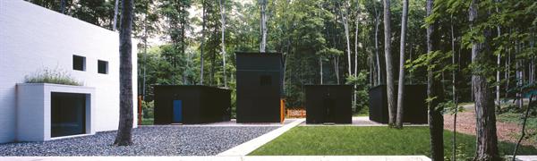 Four boxlike structures--three garages and a workshop--stand sentry duty between the parking area and the entry court. 
